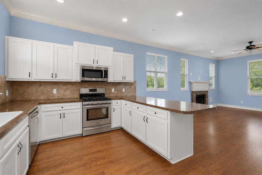 179 Ranchtown Road Elm Grove, LA 71051 - Photo 7 of 26 Open-concept kitchen featuring white cabinetry, stainless steel appliances, stone-finish countertops, and wood-finish flooring
