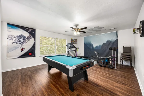 a room with wooden floor pool table and windows