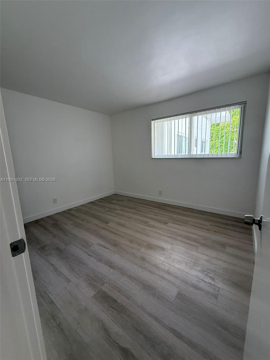 7251 Southwest 82nd Street, Unit 15 Miami, FL 33143 - Photo 7 of 15 an empty room with wooden floor and windows