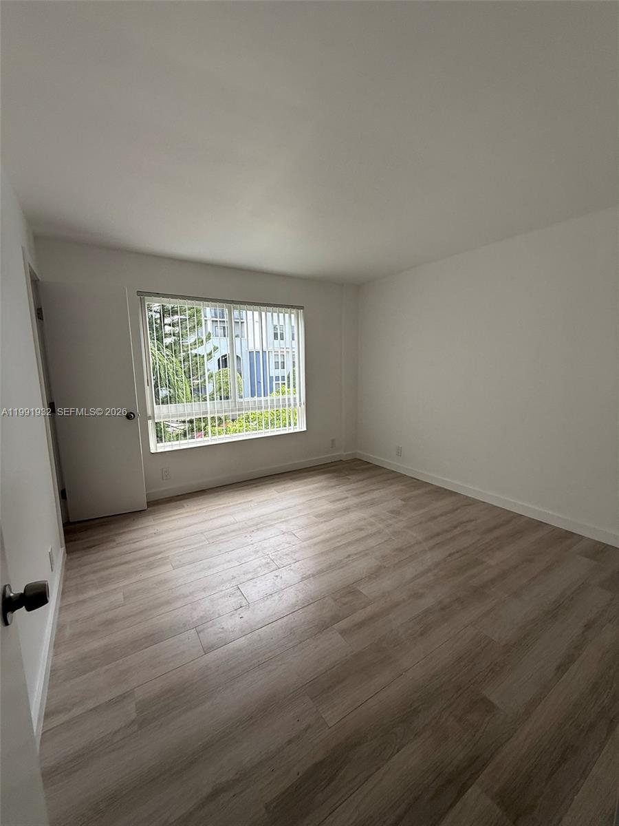 7251 Southwest 82nd Street, Unit 15 Miami, FL 33143 - Photo 9 of 15 an empty room with wooden floor and windows