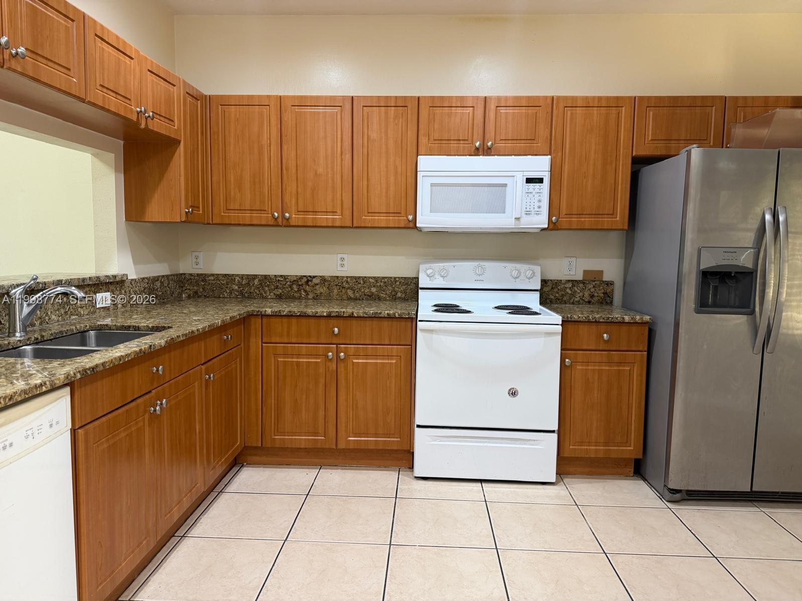 8246 Southwest 27th Street, Unit 103 Miramar, FL 33025 - Photo 4 of 17 a kitchen with a stove sink and a refrigerator