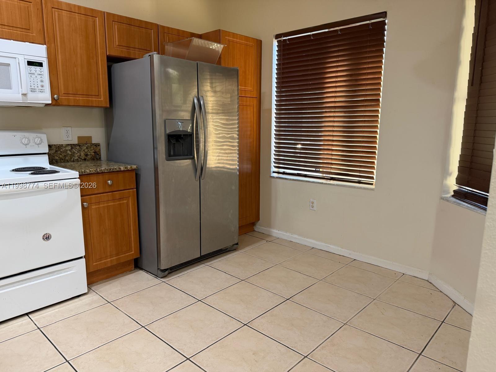 8246 Southwest 27th Street, Unit 103 Miramar, FL 33025 - Photo 5 of 17 a kitchen with stainless steel appliances a refrigerator and a stove