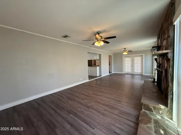 a view of an empty room with wooden floor and a ceiling fan
