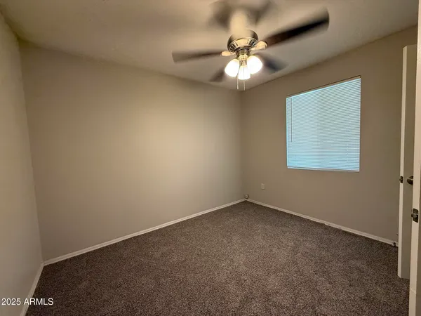 an empty room with a chandelier fan and windows