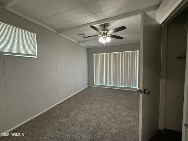 an empty room with windows and fan