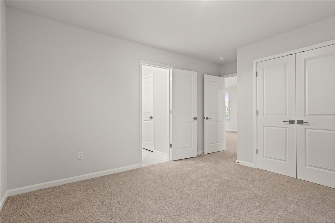 629 Sweetspire Trail, Unit 149 Seneca, SC 29678 - Photo 18 of 30 A spacious, neutral-toned room offers plush carpeting and ample natural light, with multiple doorways hinting at a versatile layout.