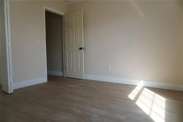 an empty room with wooden floor and closet area