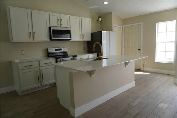 a kitchen with stainless steel appliances a stove a sink a refrigerator a microwave and cabinets