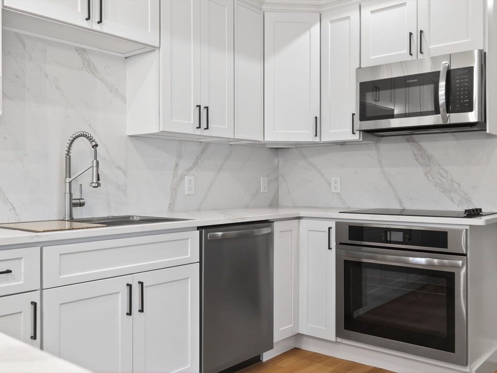 60 Stanley Street, Unit 102 Boston, MA 02125 - Photo 5 of 15 a kitchen with granite countertop white cabinets stainless steel appliances and sink