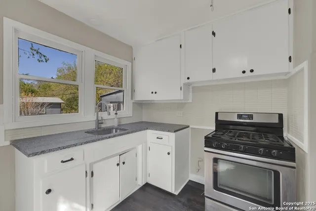 a kitchen with granite countertop white cabinets and appliances