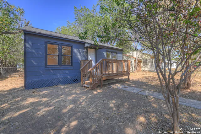 a view of a house with a yard and large tree