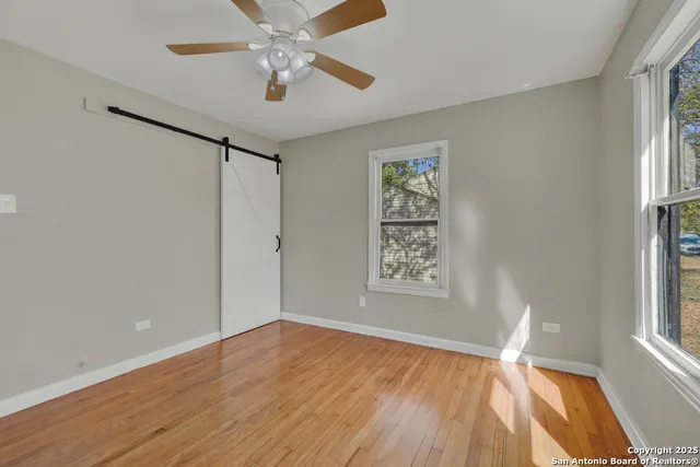 a view of empty room with wooden floor and fan