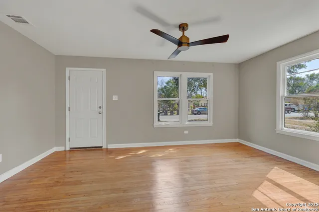 a view of empty room with wooden floor and fan