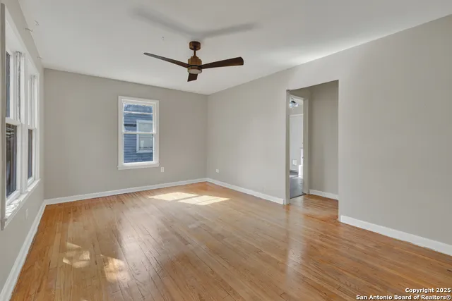a view of empty room with wooden floor and fan