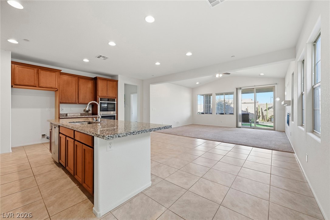 250 Dedication Avenue Henderson, NV 89011 - Photo 7 of 67 Kitchen featuring wood finish cabinets, vaulted ceiling, light tile patterned floors, recessed lighting, and light colored carpet