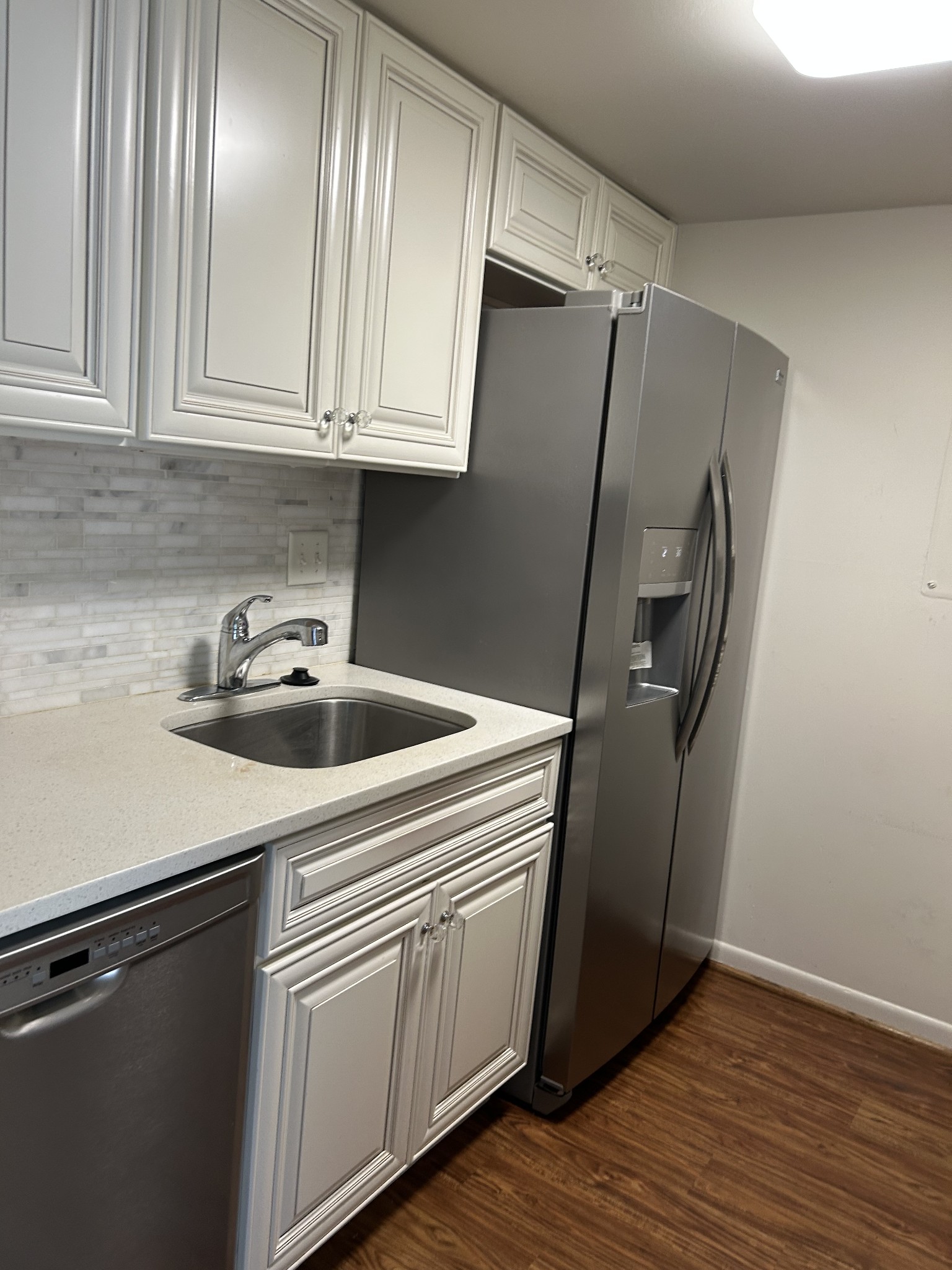 a kitchen with granite countertop a refrigerator sink and cabinets