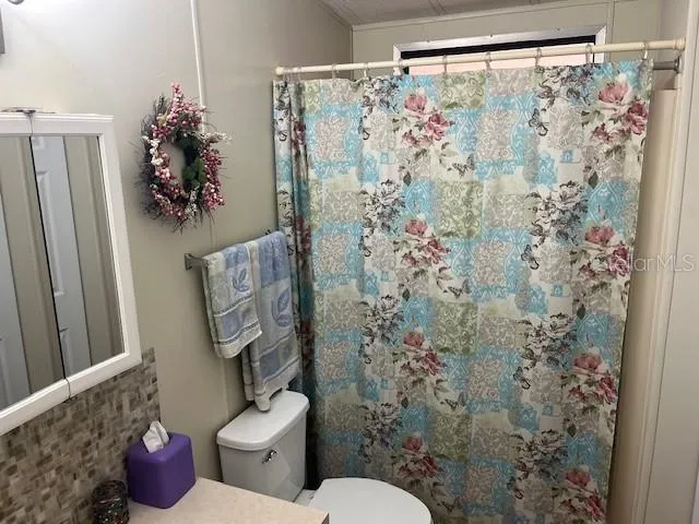 a bathroom with a toilet sink and shower curtain