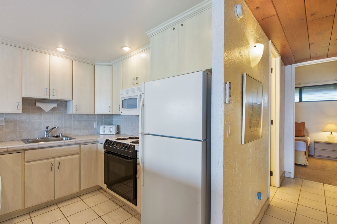 3543 Lower Honoapiilani Road, Unit F405 Lahaina, HI 96761 - Photo 25 of 30 a white refrigerator freezer sitting in a kitchen with cabinets
