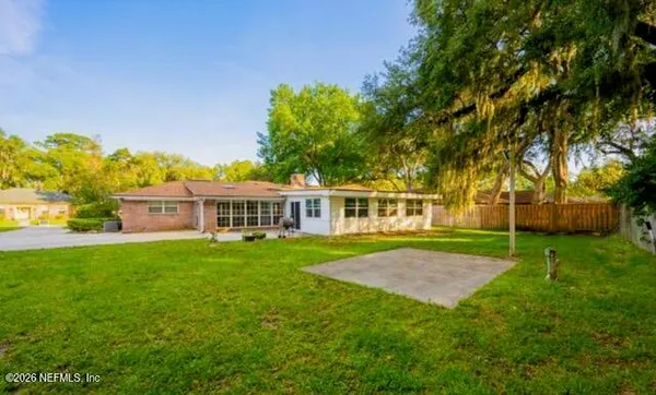 a view of a house next to a big yard and large trees