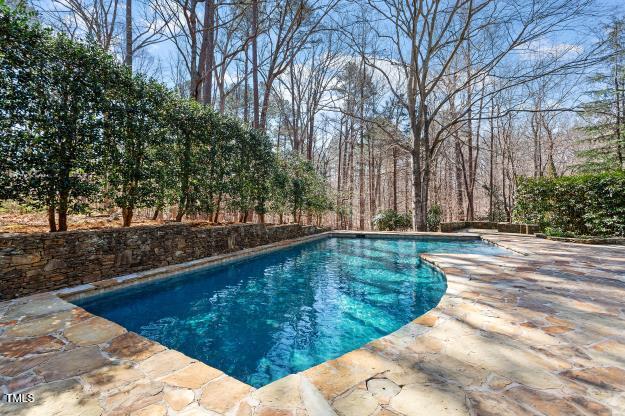 10729 Trego Trail Raleigh, NC 27614 - Photo 56 of 65 Flagstone decking encircles the pool, harmonizing with the natural surroundings.