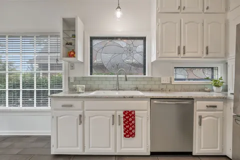 a kitchen with granite countertop white cabinets and a sink