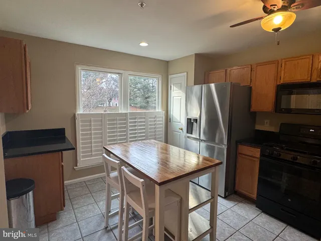 a kitchen with stainless steel appliances granite countertop a refrigerator a stove a sink a dining table and chairs