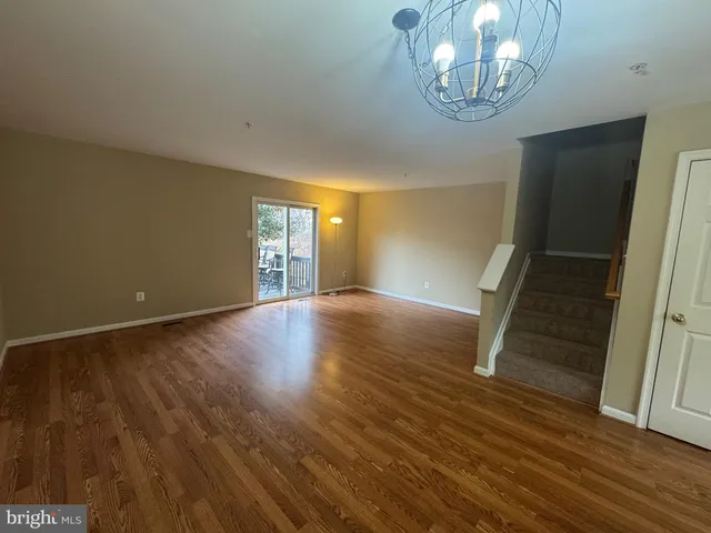 an empty room with wooden floor and staircase