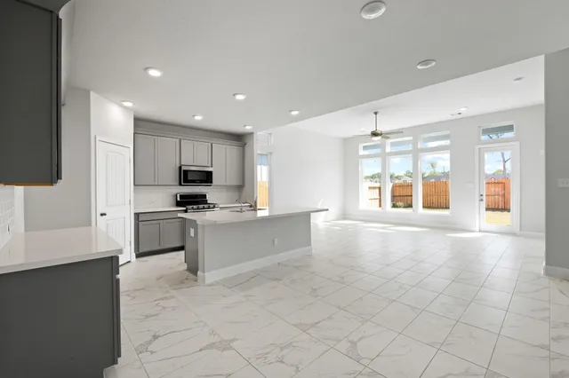 a large white kitchen with kitchen island granite countertop lots of counter top space and stainless steel appliances