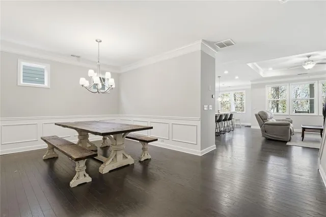 a kitchen with stainless steel appliances granite countertop a stove a sink a white cabinets and chairs with wooden floor