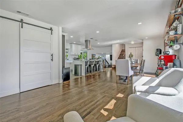 a living room with furniture and kitchen view with wooden floor