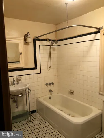 a view of a hallway with wooden floor and a bathroom