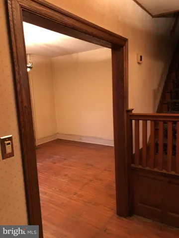 a view of an empty room with wooden floor and chandelier