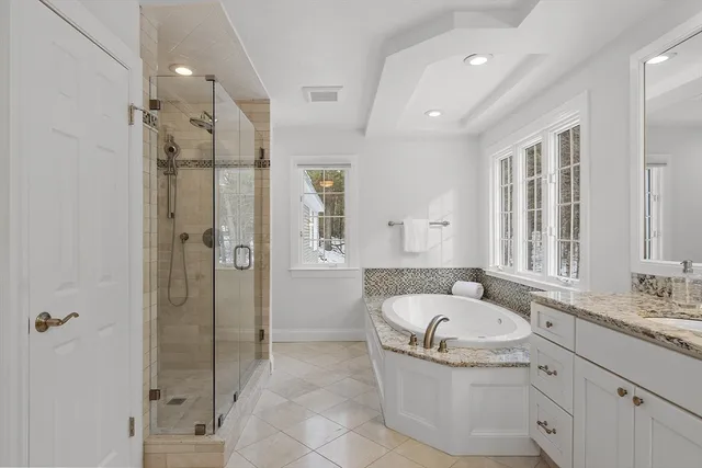 a bathroom with a granite countertop tub sink shower and mirror