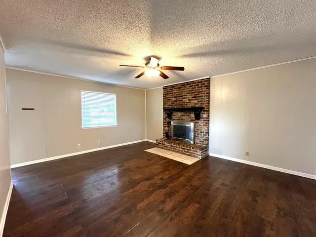 a view of empty room with wooden floor and fireplace
