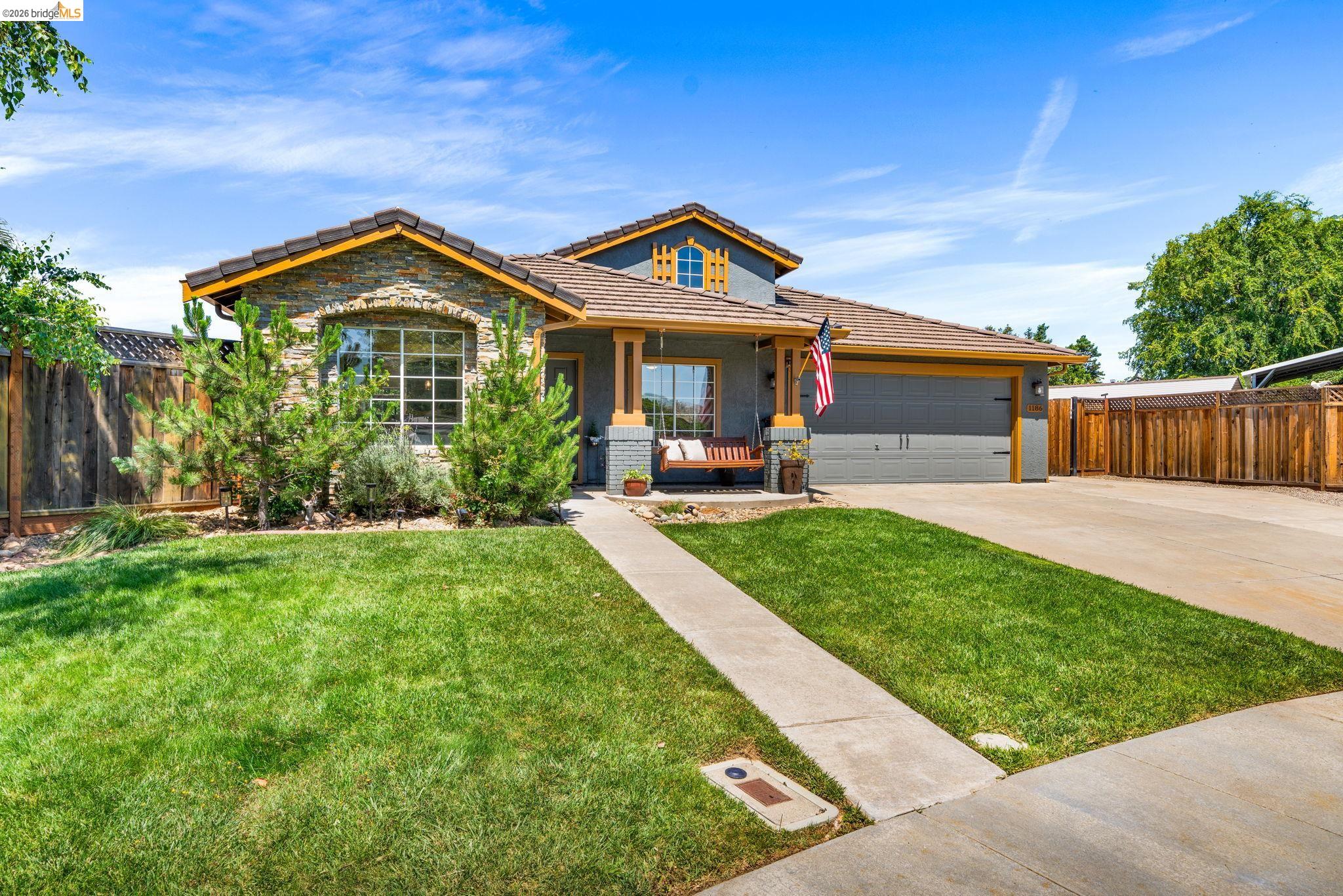 1186 El Rio Court Livermore, CA 94551 - Photo 59 of 60 Front exterior featuring a stone facade, a covered porch, a two-car garage, an established lawn, and a concrete driveway