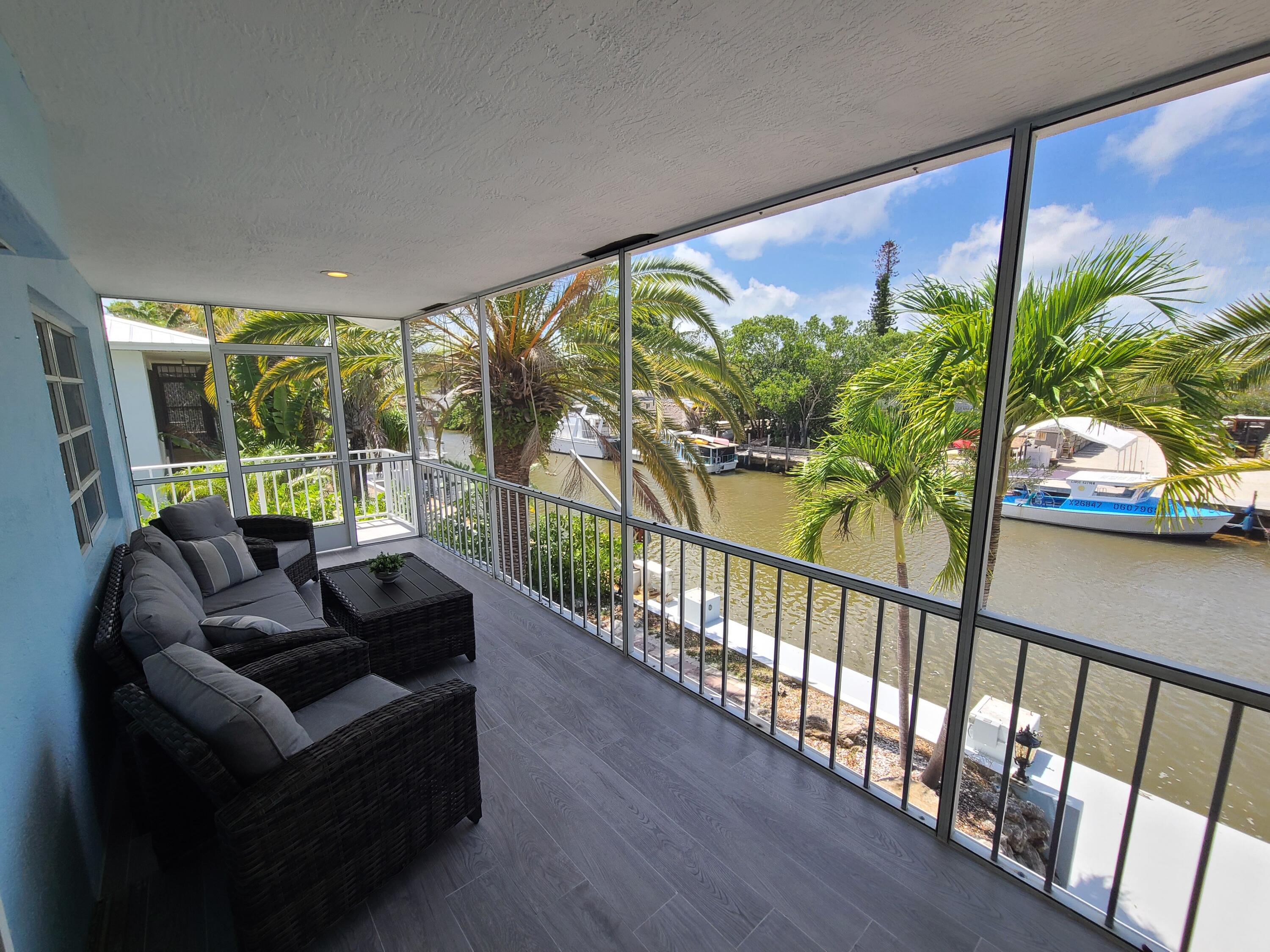 14 South Exuma Road Key Largo, FL 33037 - Photo 26 of 32 a living room with furniture with a floor to ceiling window and potted plants