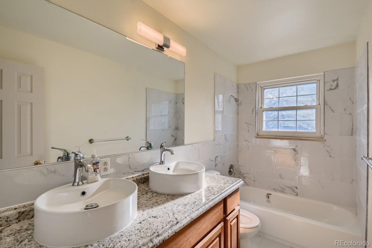 7480 Wolff Street Westminster, CO 80030 - Photo 7 of 16 a bathroom with a granite countertop tub sink and mirror