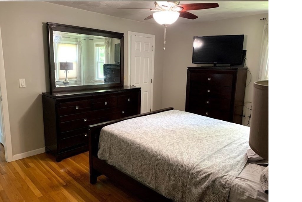 12 Burning Tree Road Natick, MA 01760 - Photo 13 of 34 a bedroom with a bed and a flat tv screen on dresser