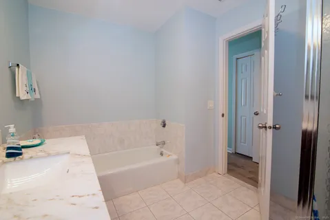a bathroom with a tub sink and mirror