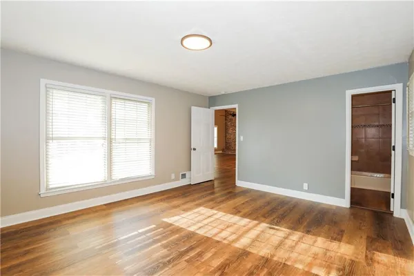 a view of an empty room with wooden floor and window