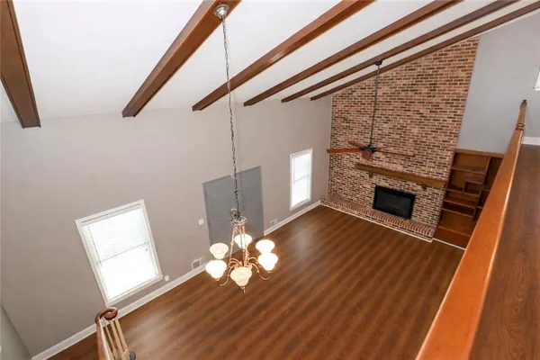 a view of an empty room with wooden floor and a fireplace