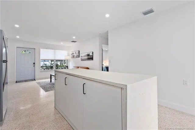 a kitchen with stainless steel appliances granite countertop white cabinets a sink a stove a refrigerator and a sink