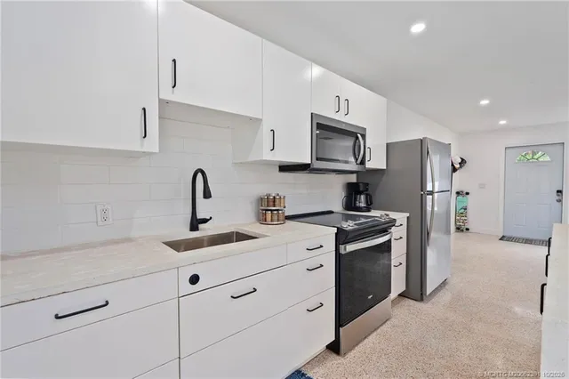 a kitchen with stainless steel appliances a refrigerator a stove a dining table and chairs