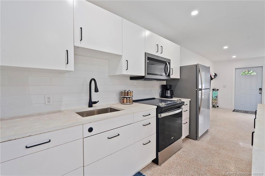 30 Southwest Hideaway Place Stuart, FL 34994 - Photo 6 of 45 a kitchen with stainless steel appliances granite countertop white cabinets a sink a stove a refrigerator and a sink