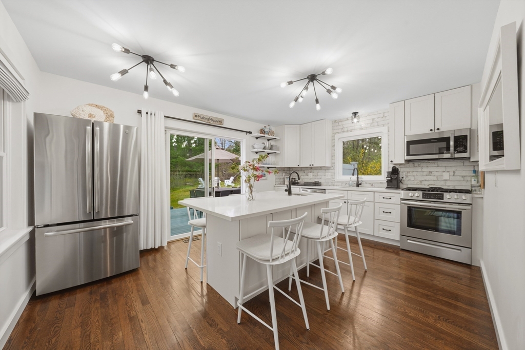 55 Ridgeview Drive Falmouth, MA 02540 - Photo 15 of 32 a kitchen with stainless steel appliances a refrigerator a stove a sink dishwasher a dining table and chairs with wooden floor