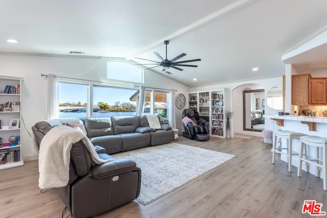 a living room with furniture kitchen view and a large window