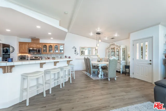 a dining room with stainless steel appliances kitchen island granite countertop a table chairs and a refrigerator