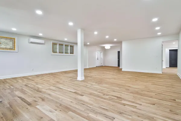 a view of an empty room with wooden floor and kitchen space