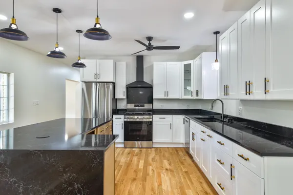 a large kitchen with stainless steel appliances granite countertop a sink a stove and a refrigerator