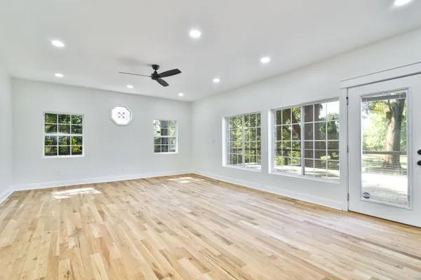 a view of empty room with wooden floor and fan